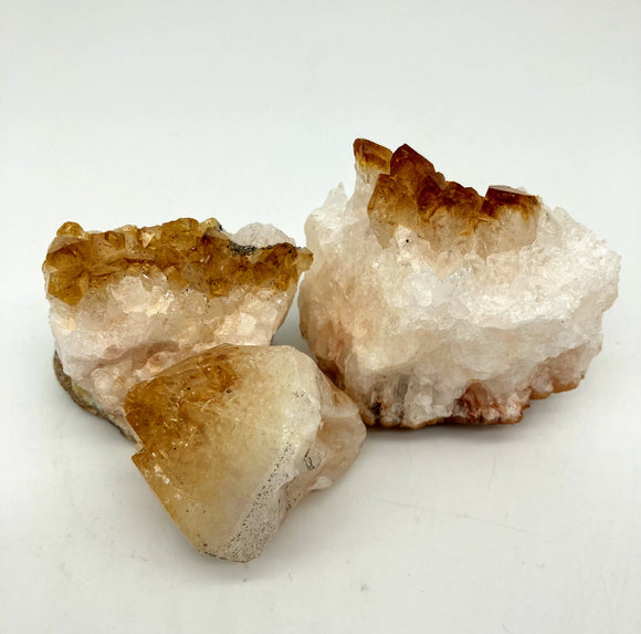 Orange and white crystal clusters (citrine) sit against a plain white background. 